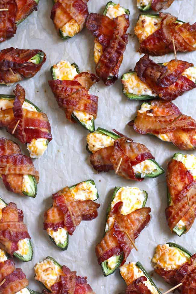 Overhead shot of just-baked bacon wrapped jalapeño poppers on a baking sheet with parchment paper.