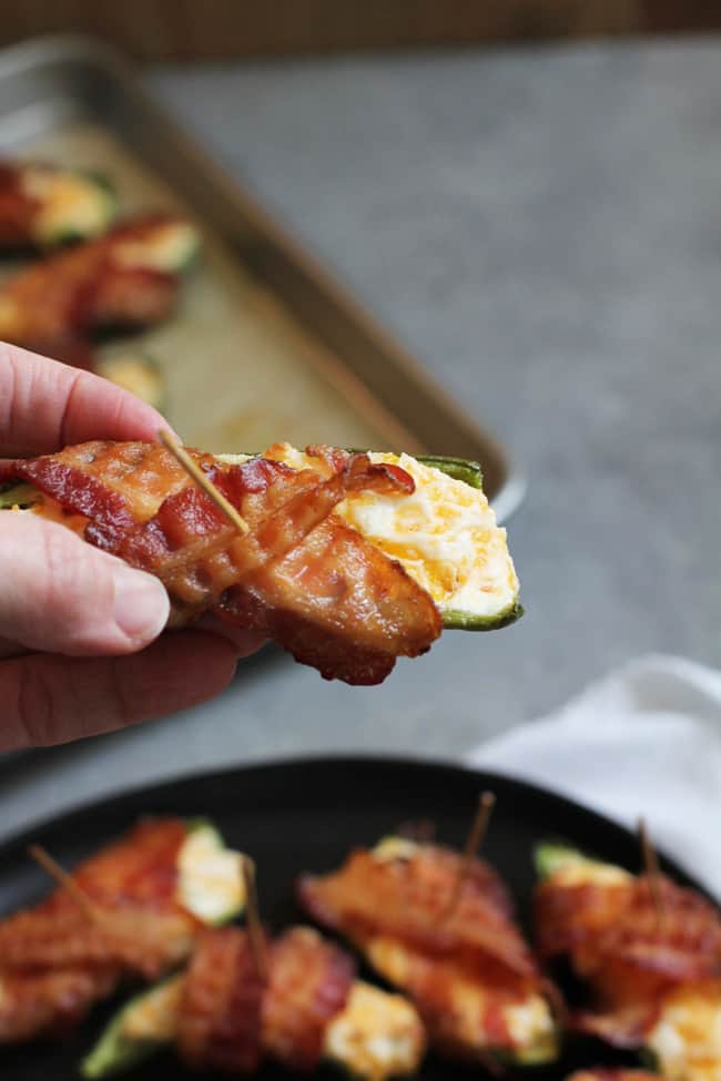 Close up shot of my hand holding a bacon wrapped jalapeño popper.