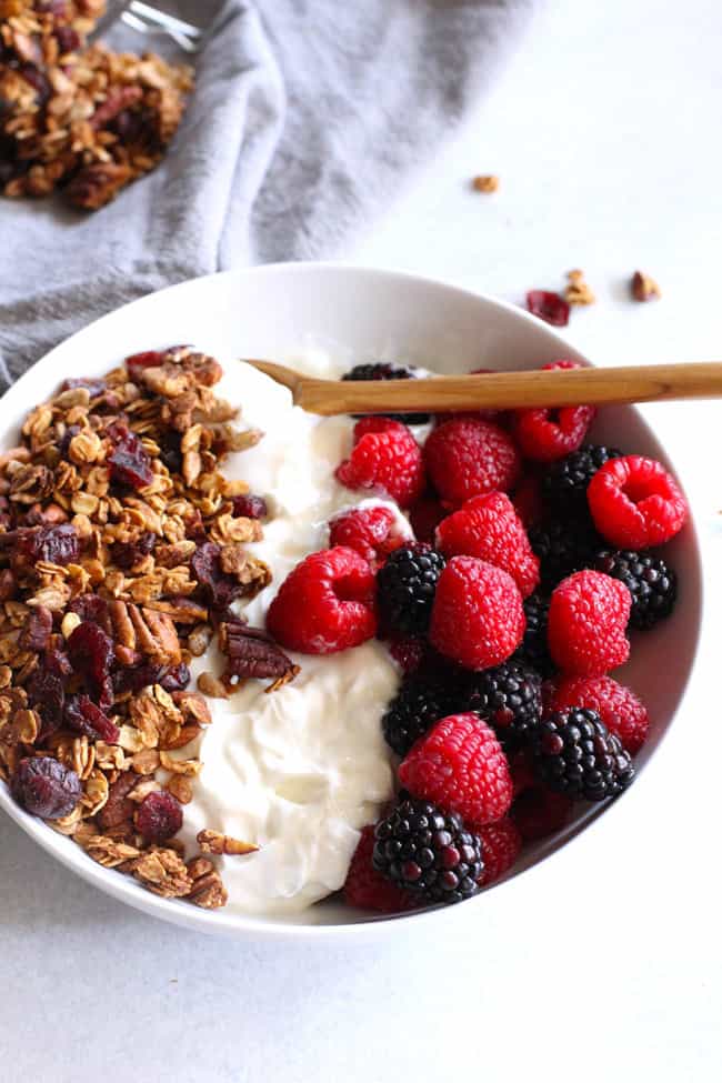 A white bowl of homemade granola, yogurt, and berries.