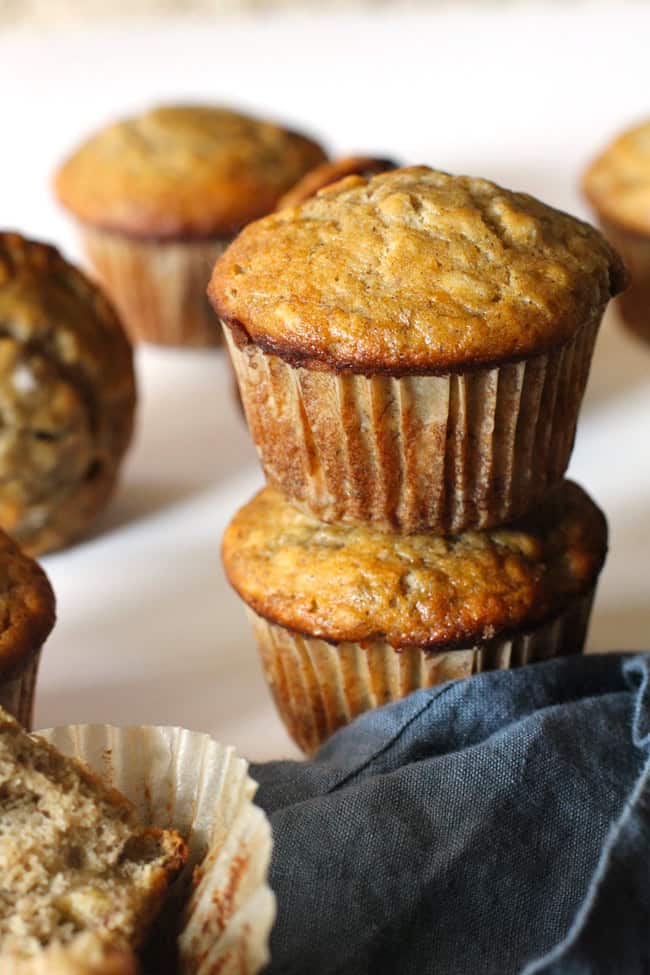 Side shot of stacked banana muffins, with a blue napkin.