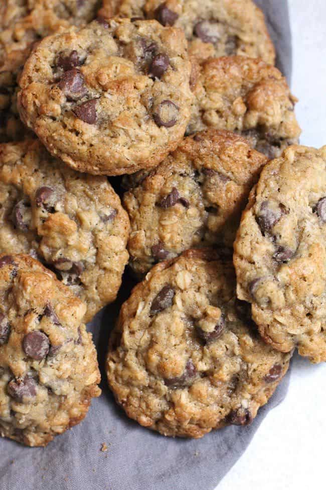 Overhead shot of oatmeal chocolate chip cookies in a pile, on a gray napkin.