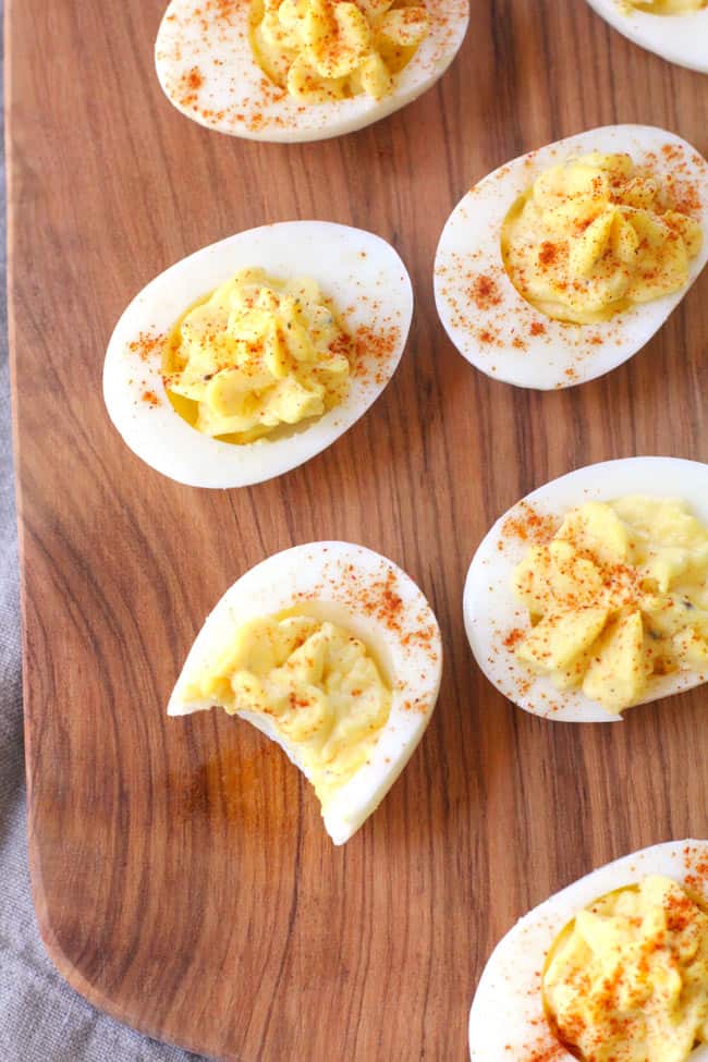 Overhead shot of deviled eggs on a wooden board.