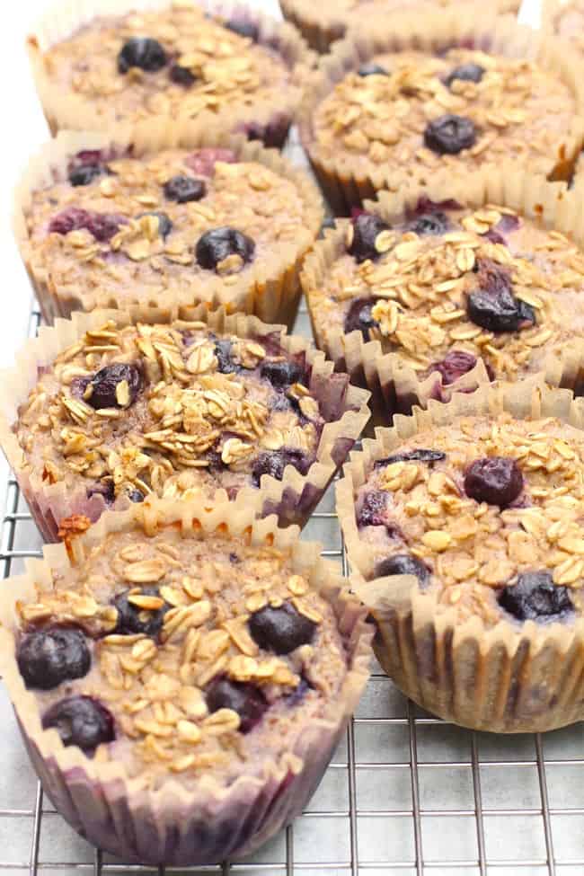 Side shot of Blueberry Baked Oatmeal Cups in jumbo liners, on a wire cooling rack.
