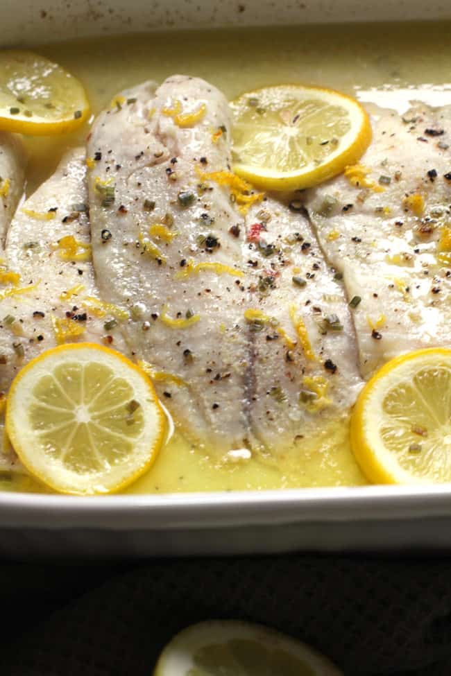 Side close-up shot of Easy Baked Lemon Butter Tilapia, with lemon slices and sauce.