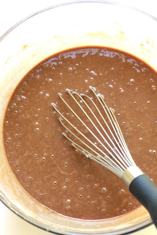 Overhead shot of a glass bowl of brownie batter, with a whisk in the middle.