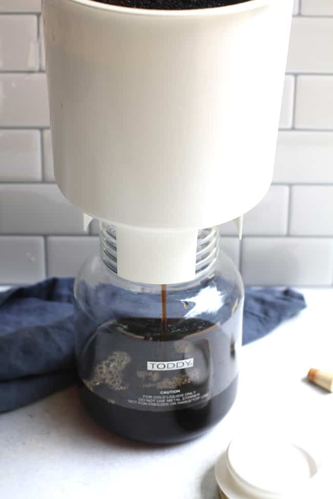 Side shot of the Toddy Cold Brew System straining into a carafe, with a white background.