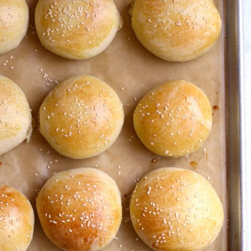 A baking sheet with just baked brioche hamburger buns.