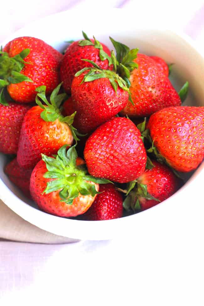 Overhead shot of a bowl of bright red strawberries.