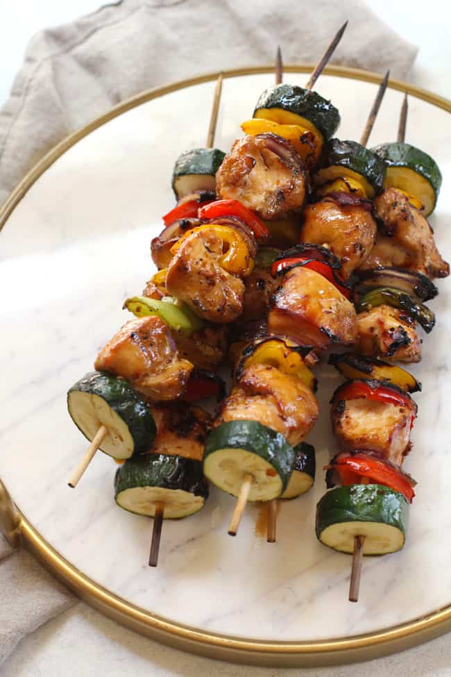Overhead shot of grilled asian chicken skewers on a white platter.
