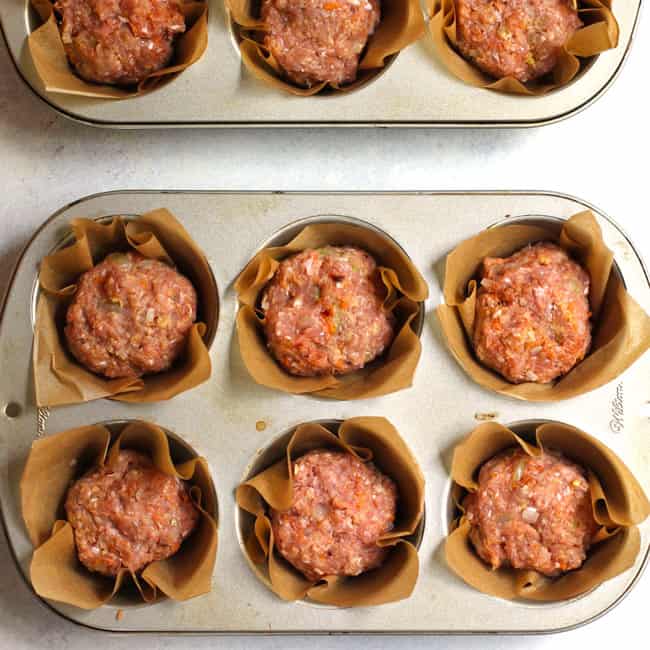 Overhead shot of pre-cooked turkey meatloaf muffins in muffin tins with parchment liners.