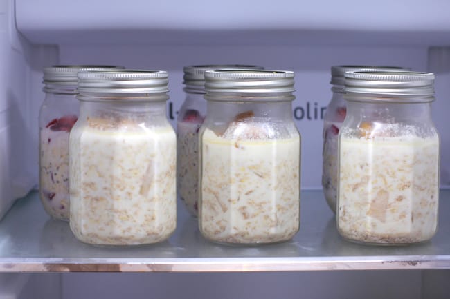 Side shot of six jars of overnight oats in the refrigerator.