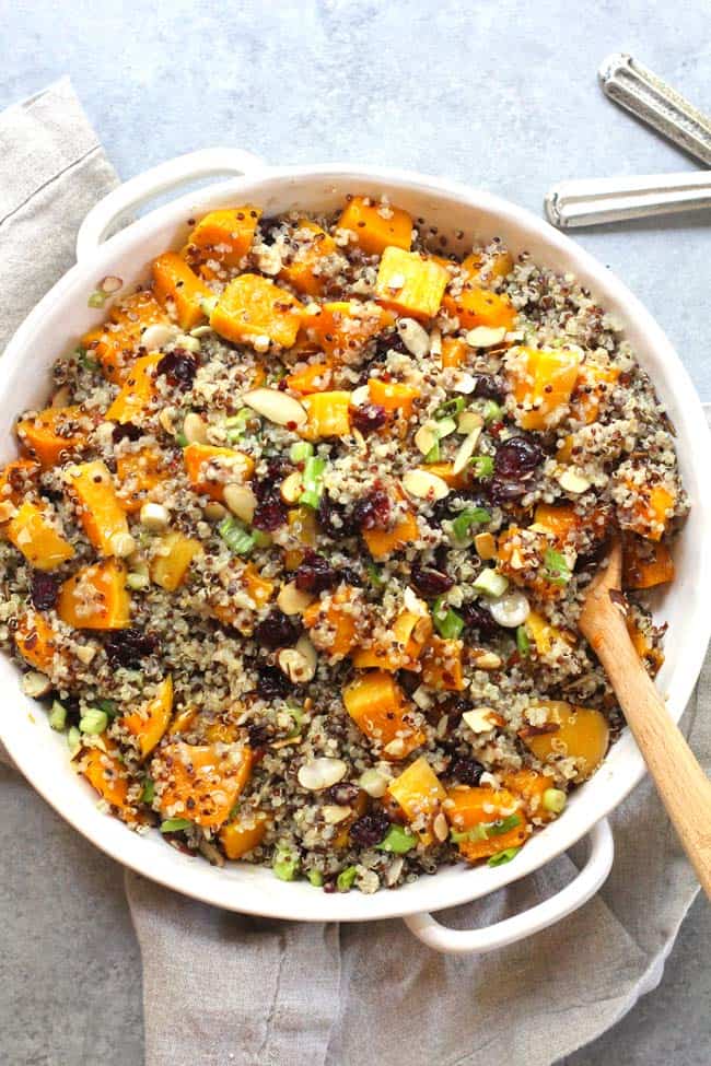 Overhead shot of a white dish of butternut squash quinoa salad, on a gray background.