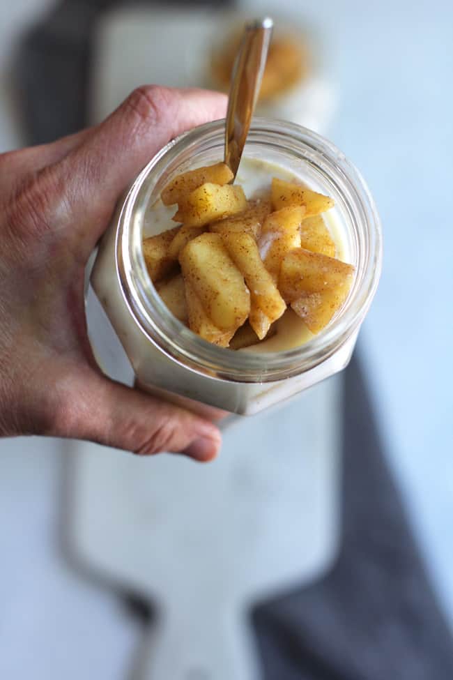 Overhead shot of my hand holding a jar of apple pie overnight oats.