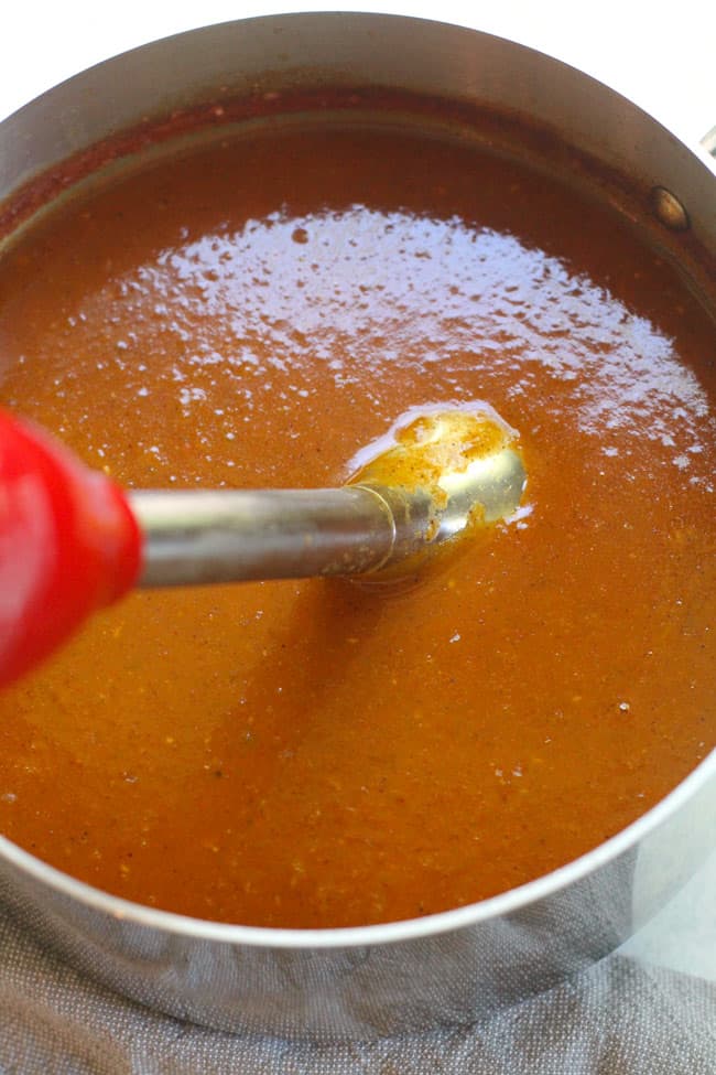 A pan of homemade enchilada sauce, with an immersion blender.