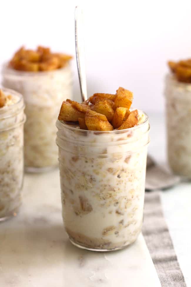 Side shot of four smaller jars of apple pie overnight oats, with one front and center.