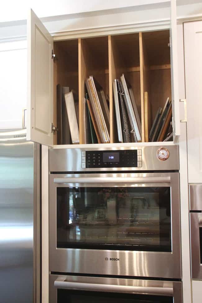 Open cabinet above ovens showing sheet pans.