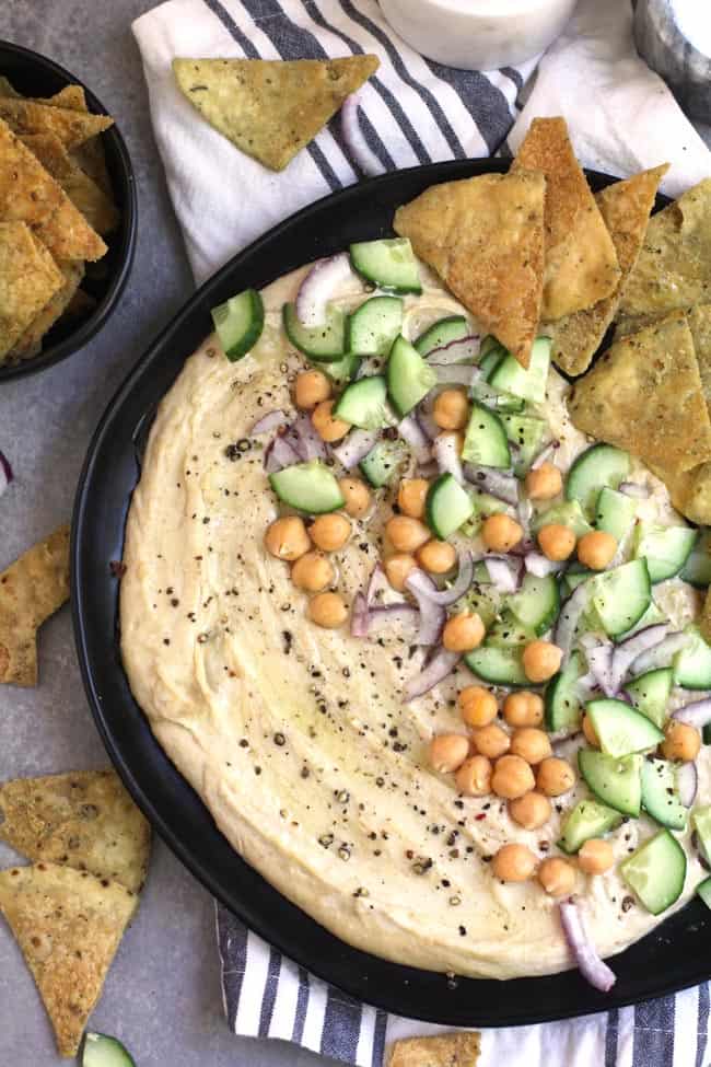 Overhead shot of a plate of healthy hummus spread, with veggies and pita chips.