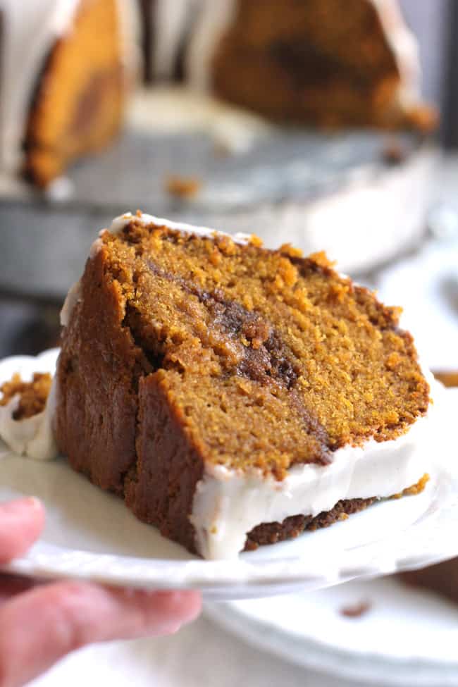 Side shot of a slice of pumpkin streusel cake on a serving plate with the cake in the background.