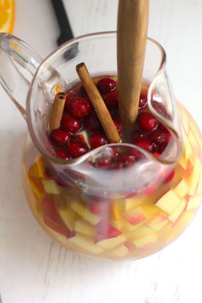Overhead shot of a glass pitcher filled with apple cider sangria, filled with fruit.