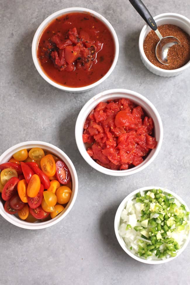 Overhead shot of small bowls of tomatoes, onions, canned tomatoes, and taco seasoning.
