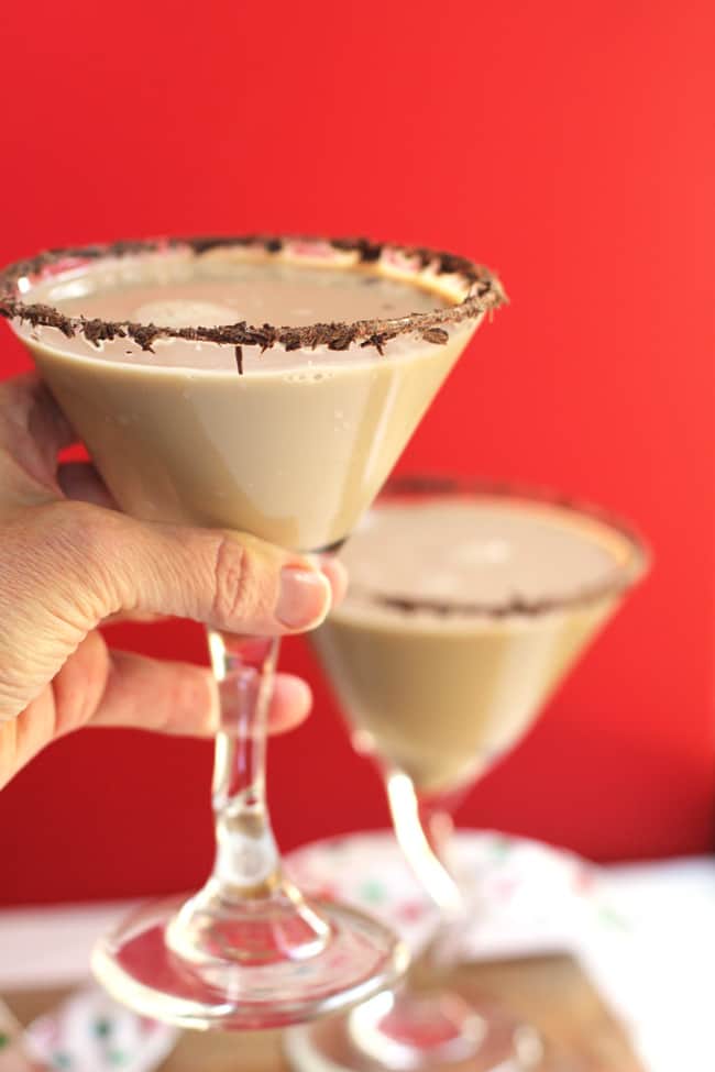 My hand holding a chocolate martini up over one in the background, again a red background.