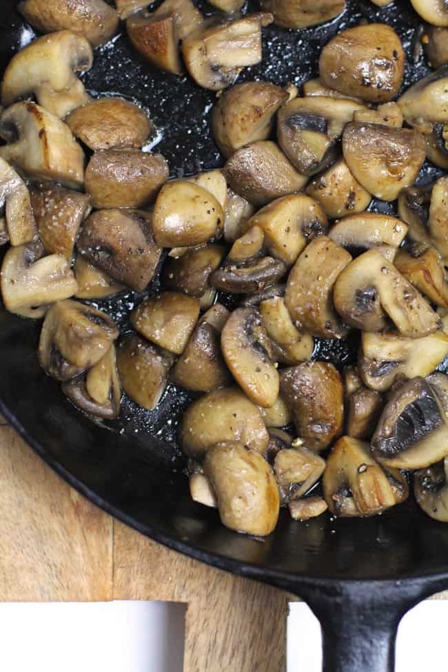 Close up shot of a corner of a skillet with browned mushrooms.