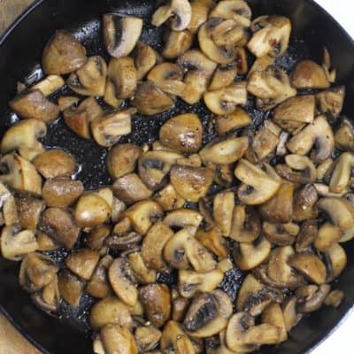 Overhead shot of a cast iron skillet filled with browned mushrooms.