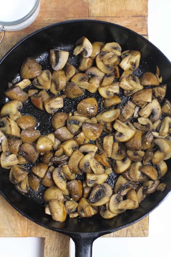 Overhead shot of a cast iron skillet filled with browned mushrooms.