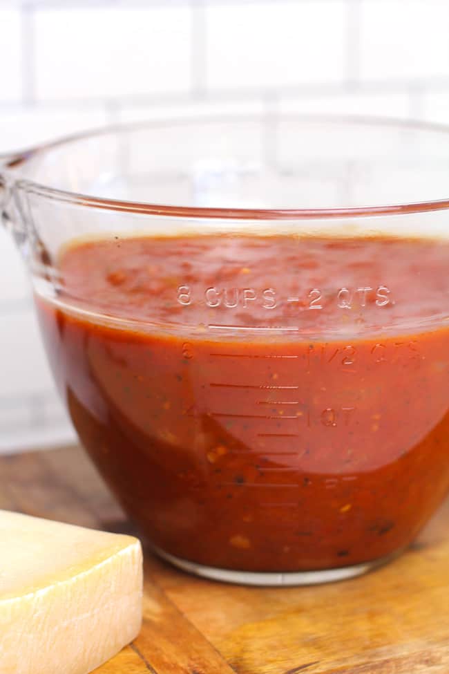 Side shot of a large measuring cup filled to about 6 cups of marinara sauce.