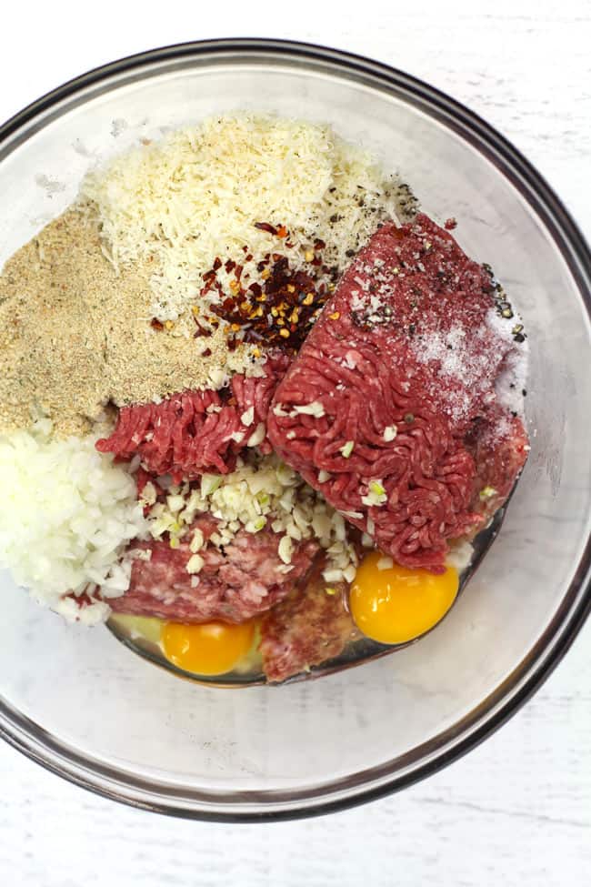 Overhead shot of a glass bowl of Italian meatball ingredients, before rolling into balls.
