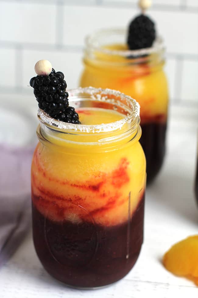 Side shot of two jars of blackberry peach frozen margaritas.