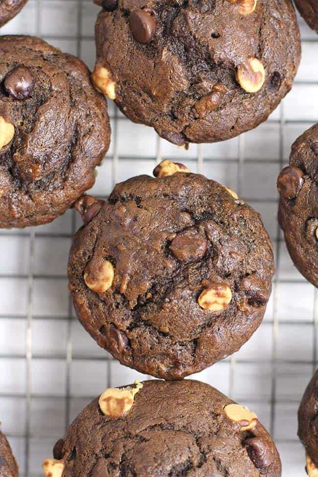 Closeup shot of a few chocolate peanut butter banana muffins, on a cooling rack.