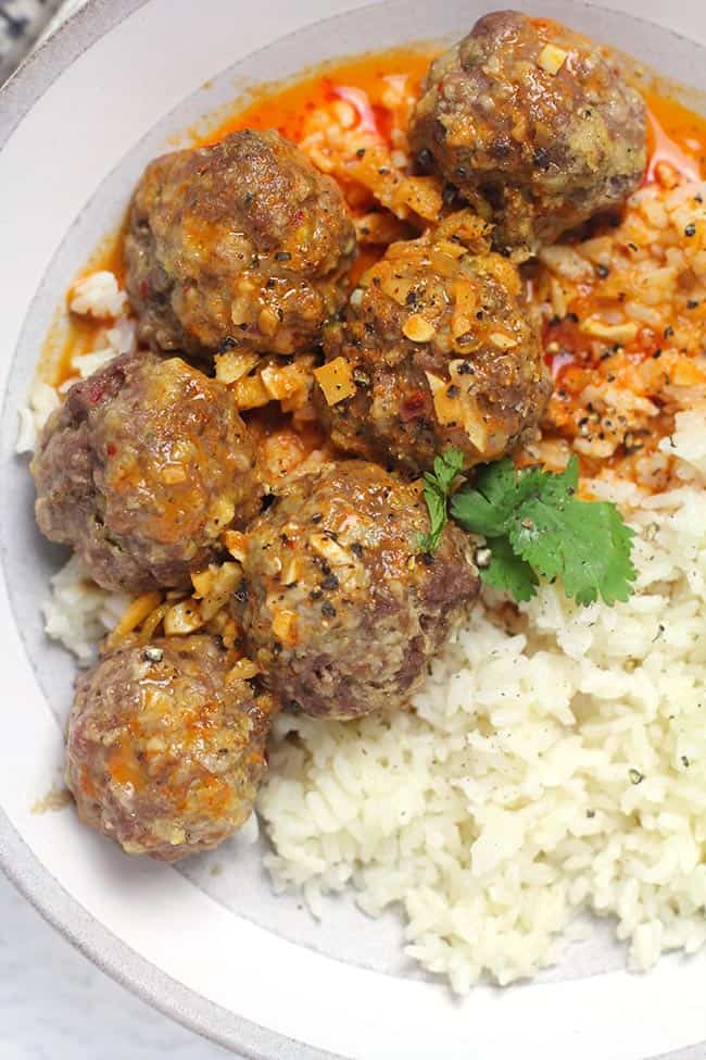 Close up shot of a bowl of curried meatballs and rice.