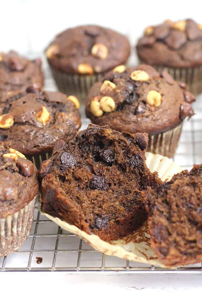 Side shot of a half of a chocolate peanut butter banana muffins, with other muffins in the background.