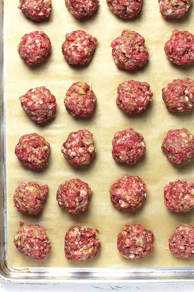 Overhead shot of a sheet pan of Italian meatballs, on parchment paper.