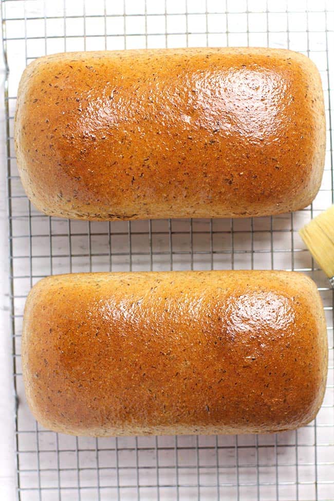 Overhead shot of two loafs of whole wheat honey bread on a wire cooling rack.