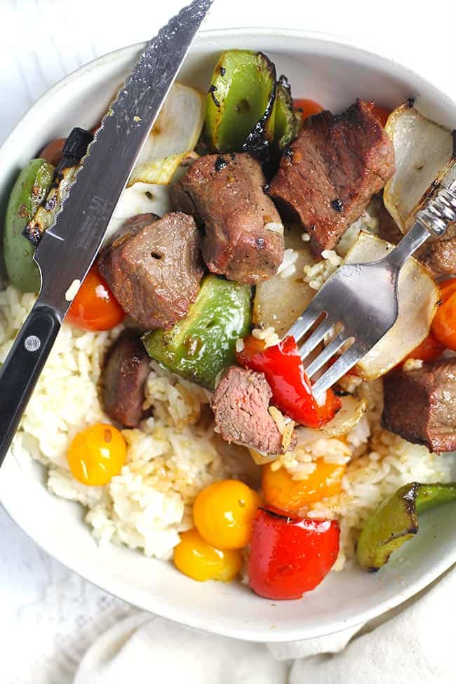 Overhead shot of a bowl of steak kabobs and veggies, over rice.