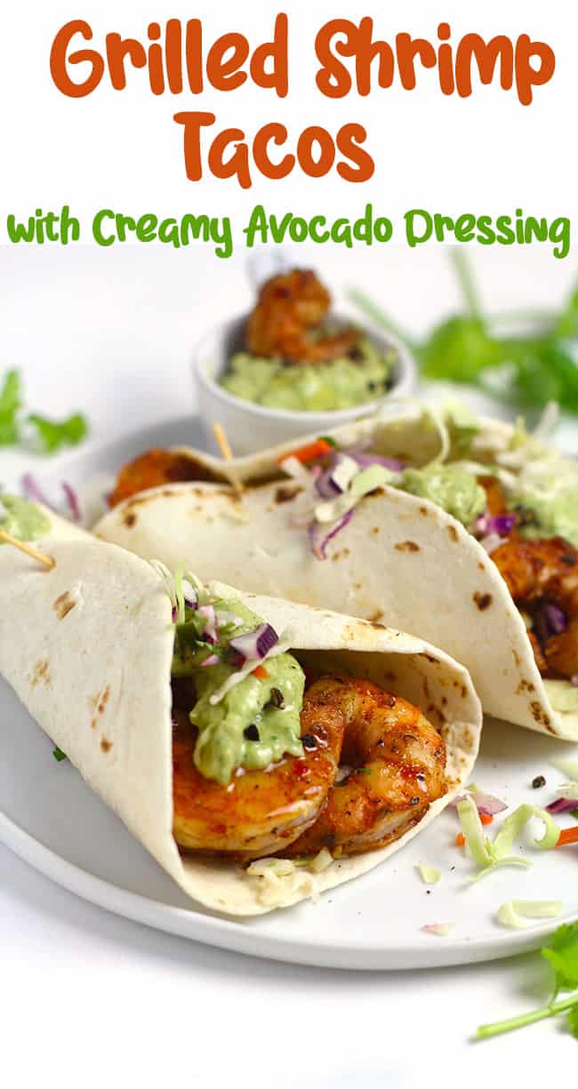 Side view of two grilled shrimp tacos with creamy avocado dressing.
