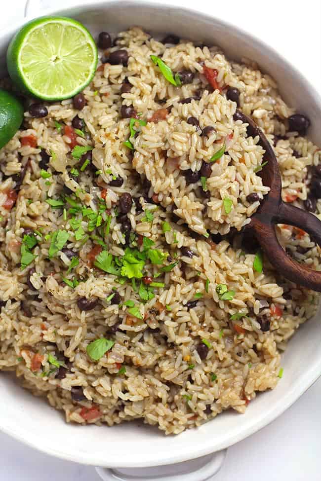 Closeup shot of a dish of Spanish Rice and Beans, with a wooden spoon.