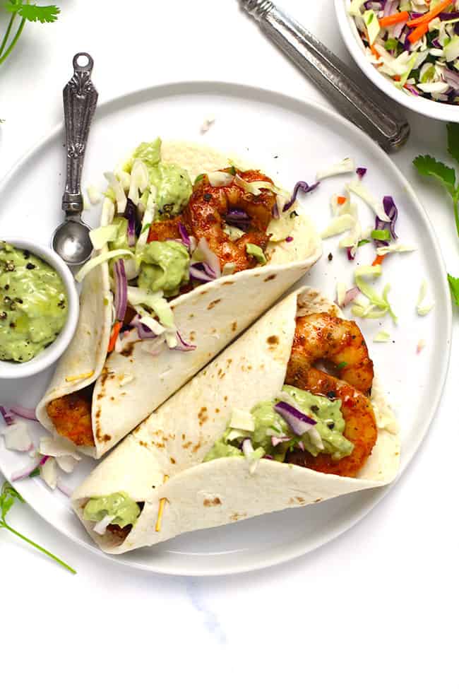 Overhead shot of a white plate of grilled shrimp tacos.