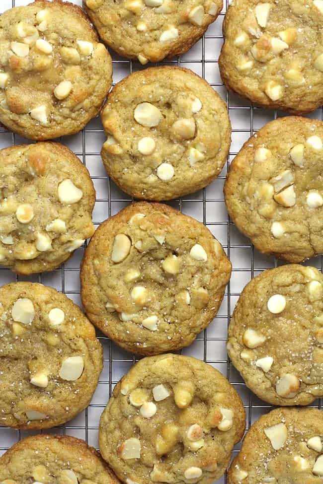 A bunch of white chocolate macadamia nut cookies on a cooling rack.