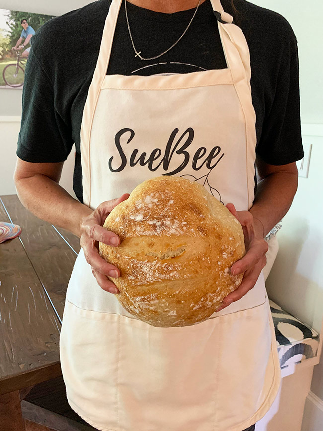 Me in my SueBee apron, holding a loaf of sourdough.