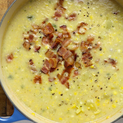 Overhead shot of a stock pot of corn chowder with bacon on the top.