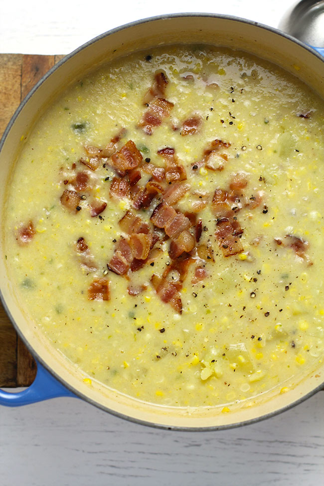 Overhead shot of a stock pot of corn chowder with bacon on the top.