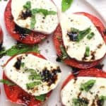 A plate of caprese salad, drizzled with balsamic glaze.