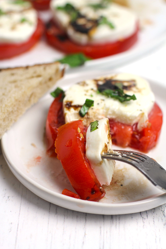 A small plate of caprese salad with a bite on a fork.