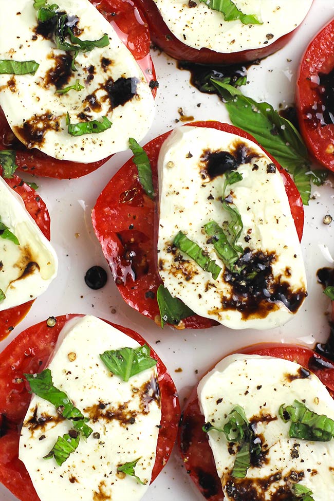 Closeup on the plate of caprese salad with balsamic glaze and basil.