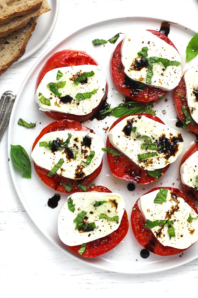 A plate of eight caprese salad tomatoes and fresh mozzarella.