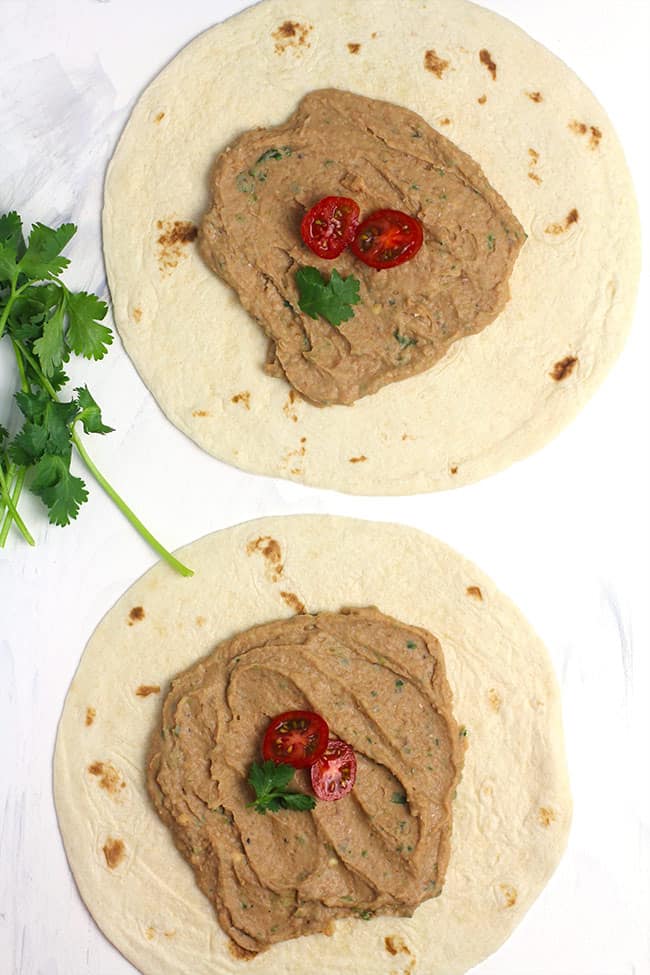 Two tortillas with refried beans on top.