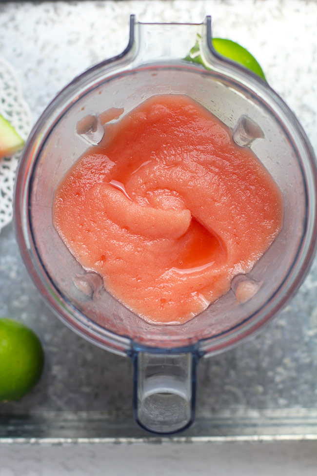 A blender full of watermelon frose on a gray tray.